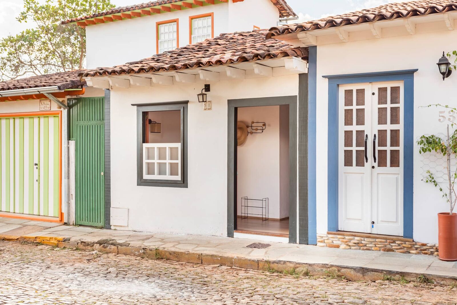 Fachada colonial da Casa Boutique, com portas azul e verde, na rua de pedra do centro histórico de Pirenópolis