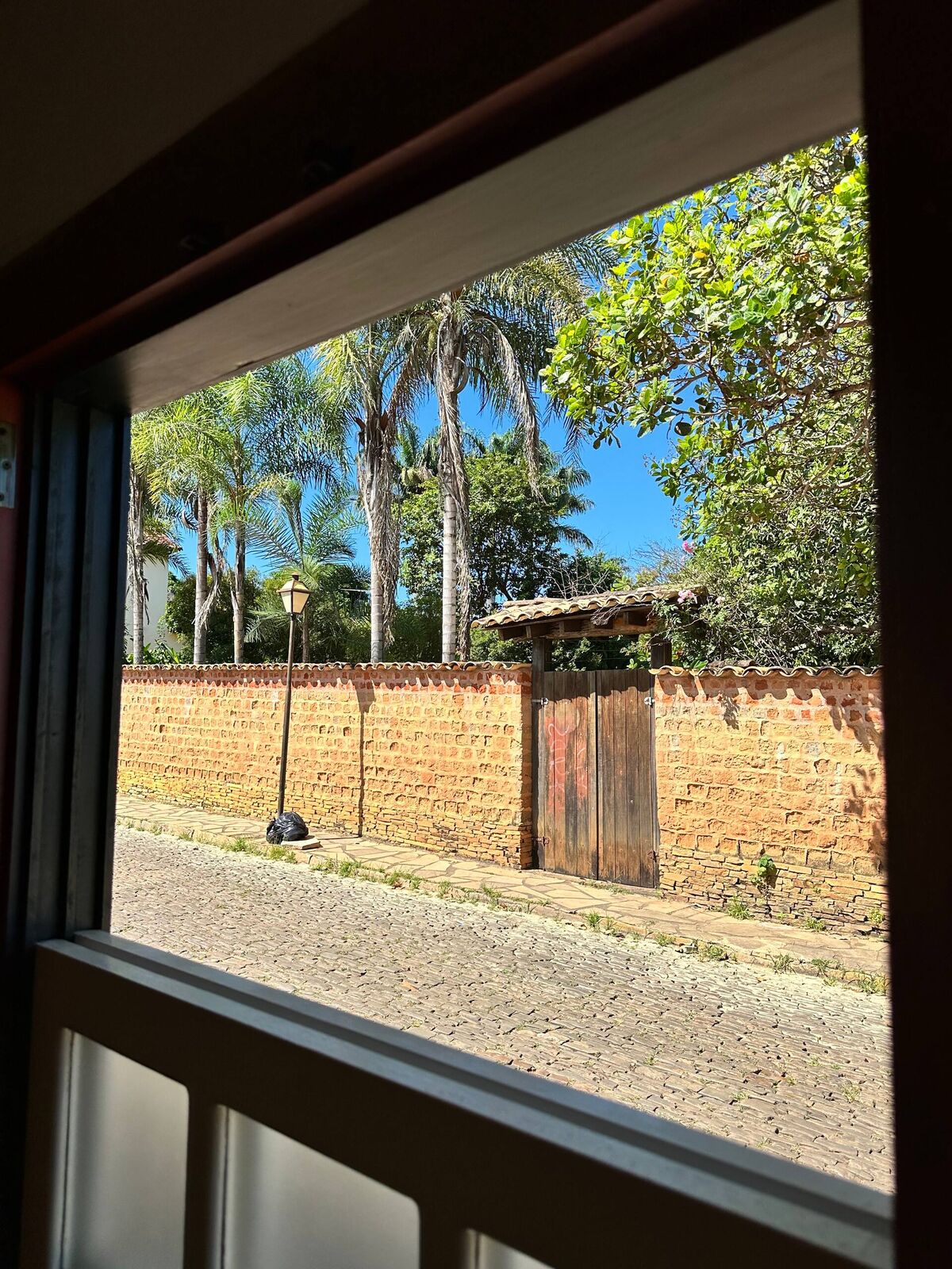 Vista da janela da casa para a rua de pedra e o muro de adobe do centro histórico